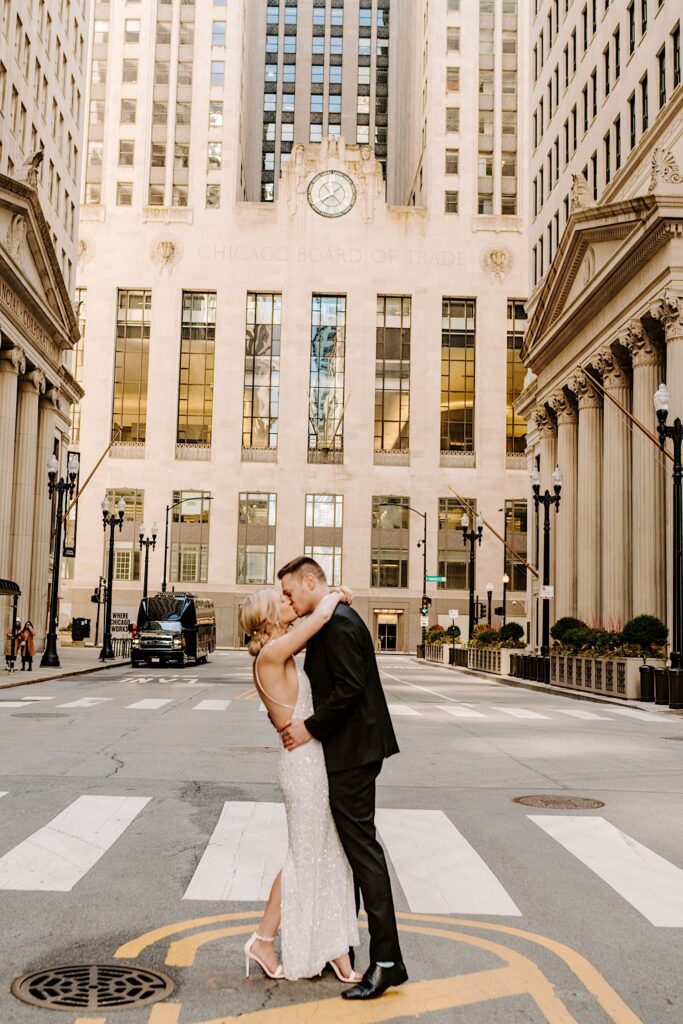 A bride and groom kiss while standing in the middle of a street in downtown Chicago