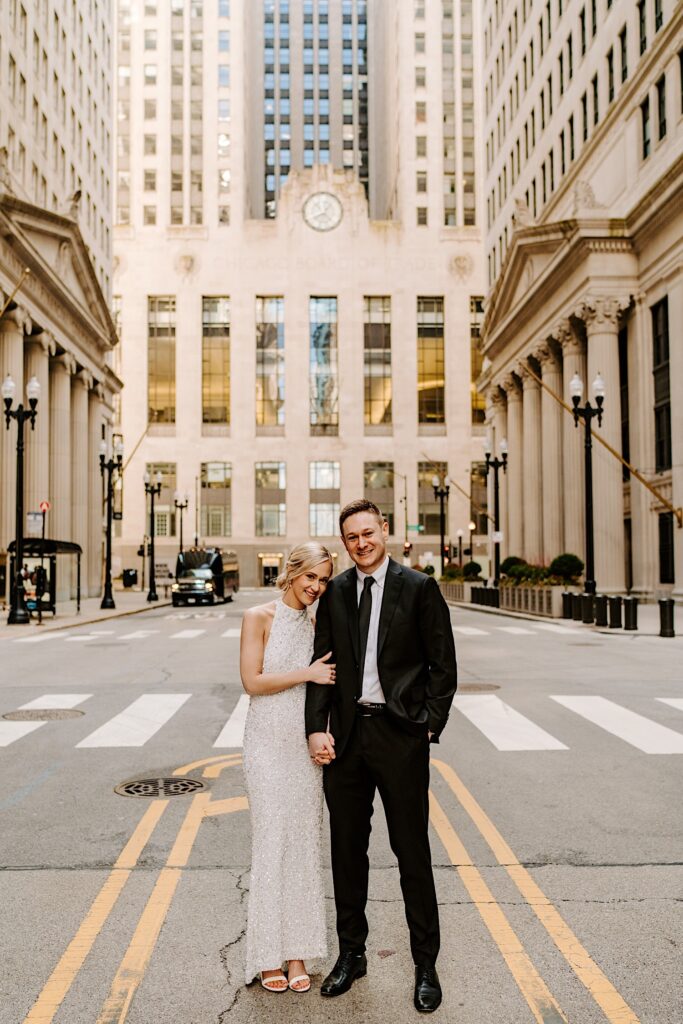 A bride and groom pose for a portrait photo in the middle of a street in downtown Chicago