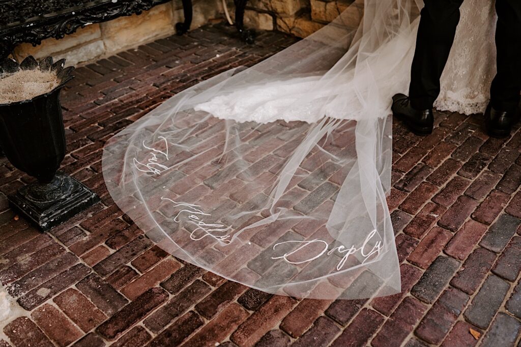 Detail photo of a bride's wedding dress lying on a brick patio