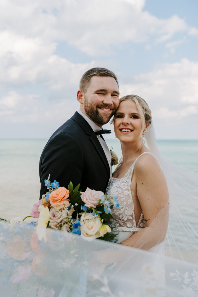 Bride and Groom stand with their heads pressed together on the Chicago lakefront overlooking Lake Michigan for a beautiful wedding portrait. 