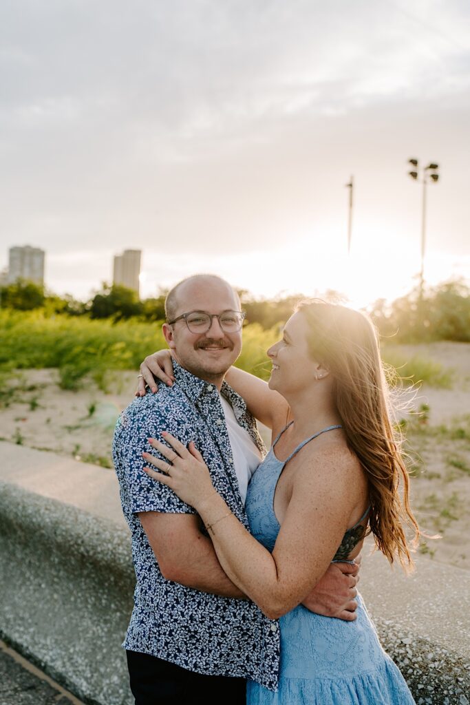 A couple smiles while looking at each other and watching the sunset at North Avenue Beach in Chicago. 