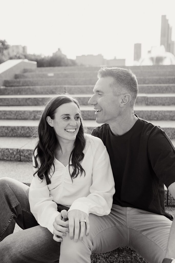 A couple laughs at something in the distance as they take a rest on some steps in Grant Park Chicago.  You can see Buckingham fountain in the distance.